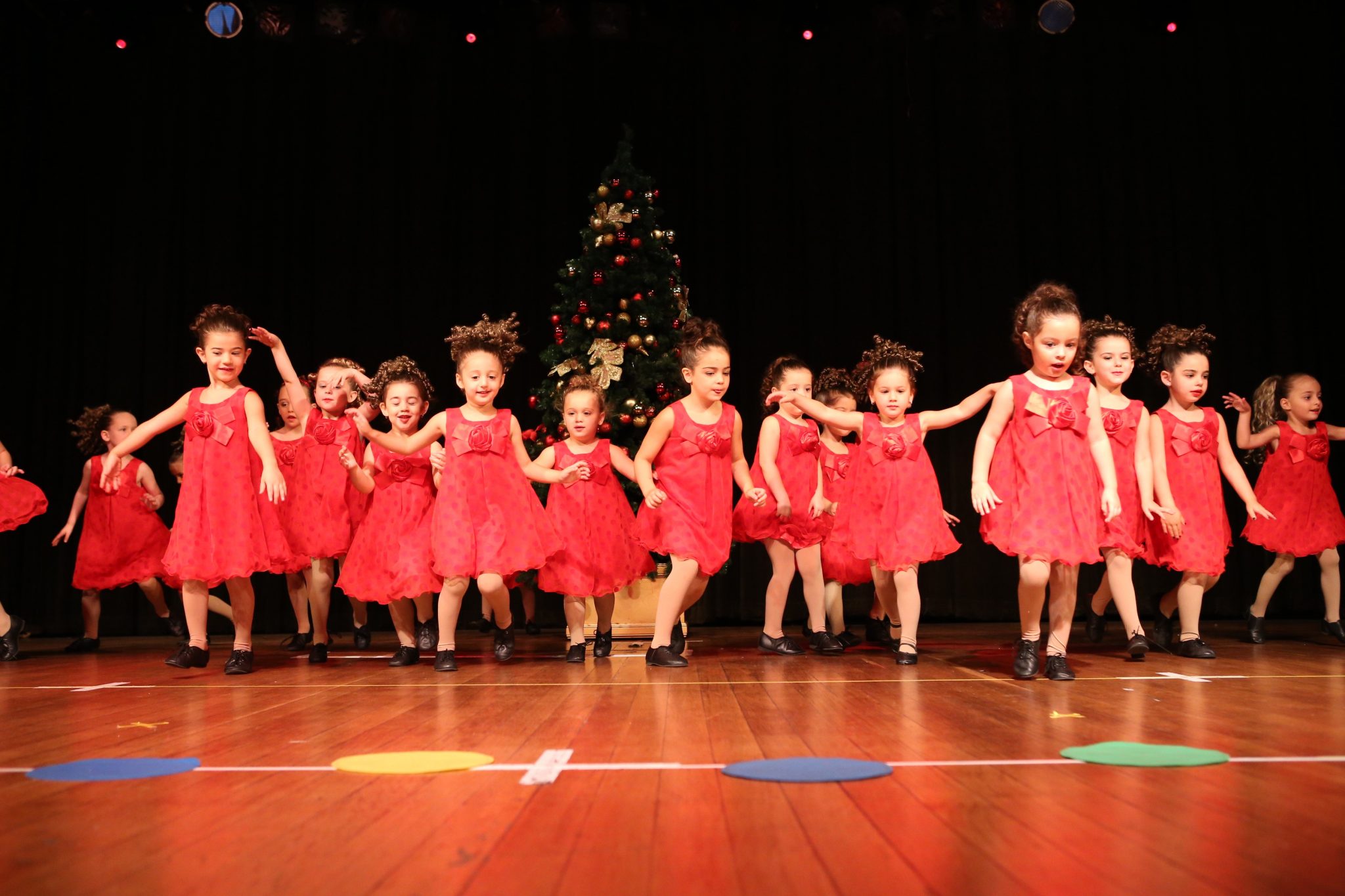 Toddlers in red dresses performing in a dance concert