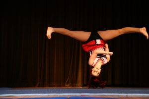 Teenage girl upside down while performing an acrobatics move