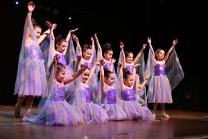 Young girls, dressed as purple fairies strike a pose at dance concert