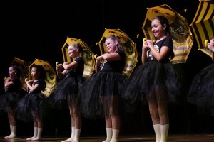 Young girls with bee umbrellas dance