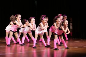 Toddler girls, in pink and white, dance