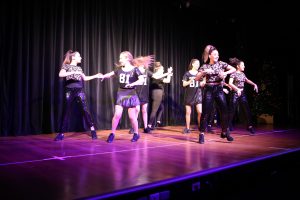 Eight teenage girls dressed in black dance