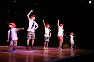 Five young boys perform hip hop moves to crowd
