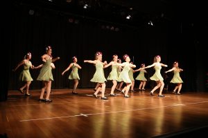Girls in green dresses dancing in concert