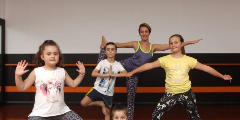 Young children performing yoga with teacher